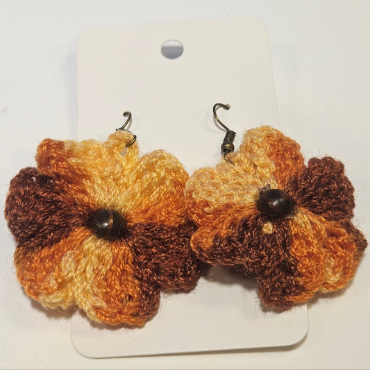 Pair of brown and beige crocheted flower earrings on a white card.