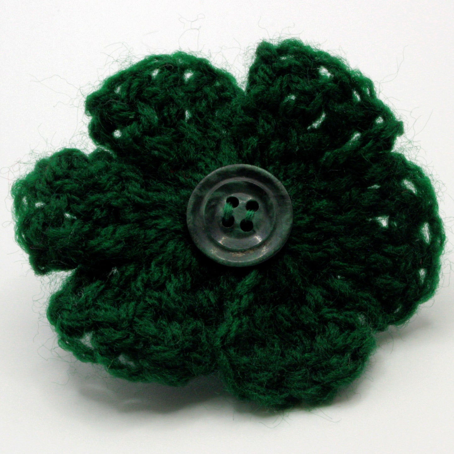 Green crocheted flower with a button center on a white background