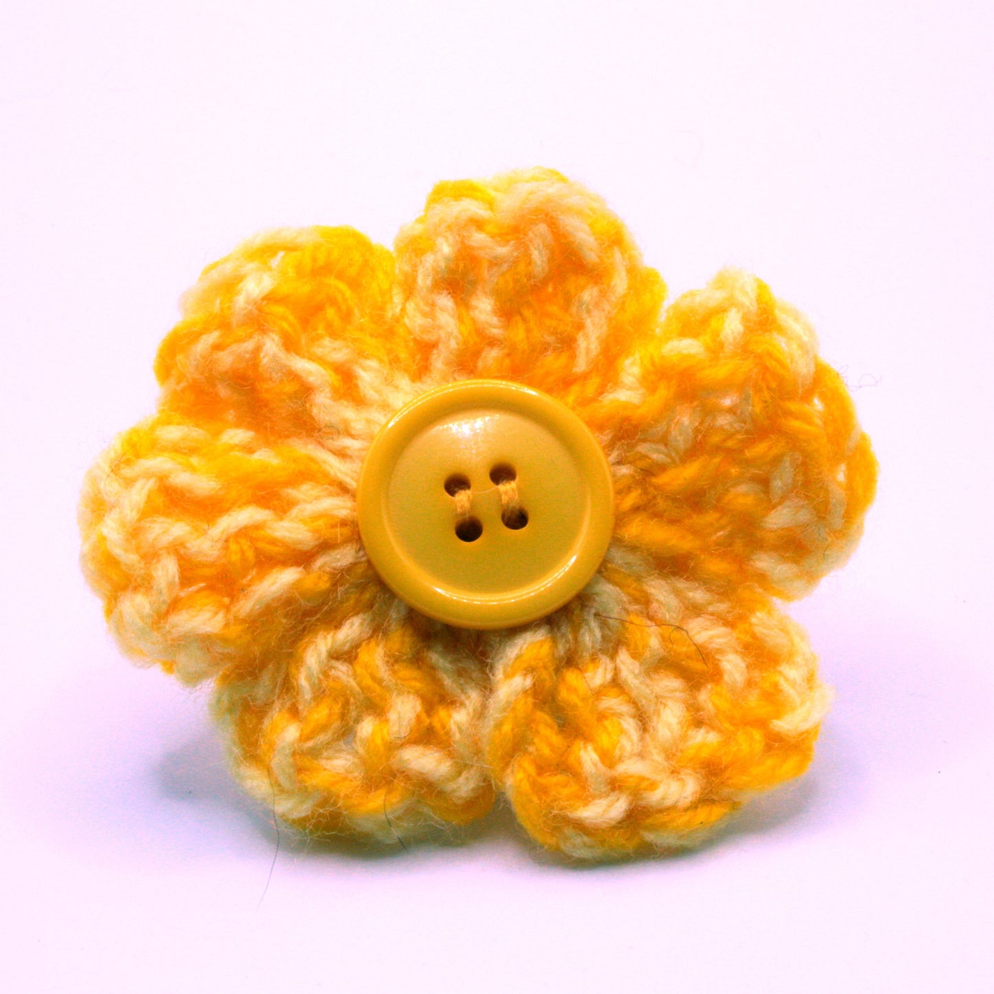 Yellow knitted flower with a button center on a white background
