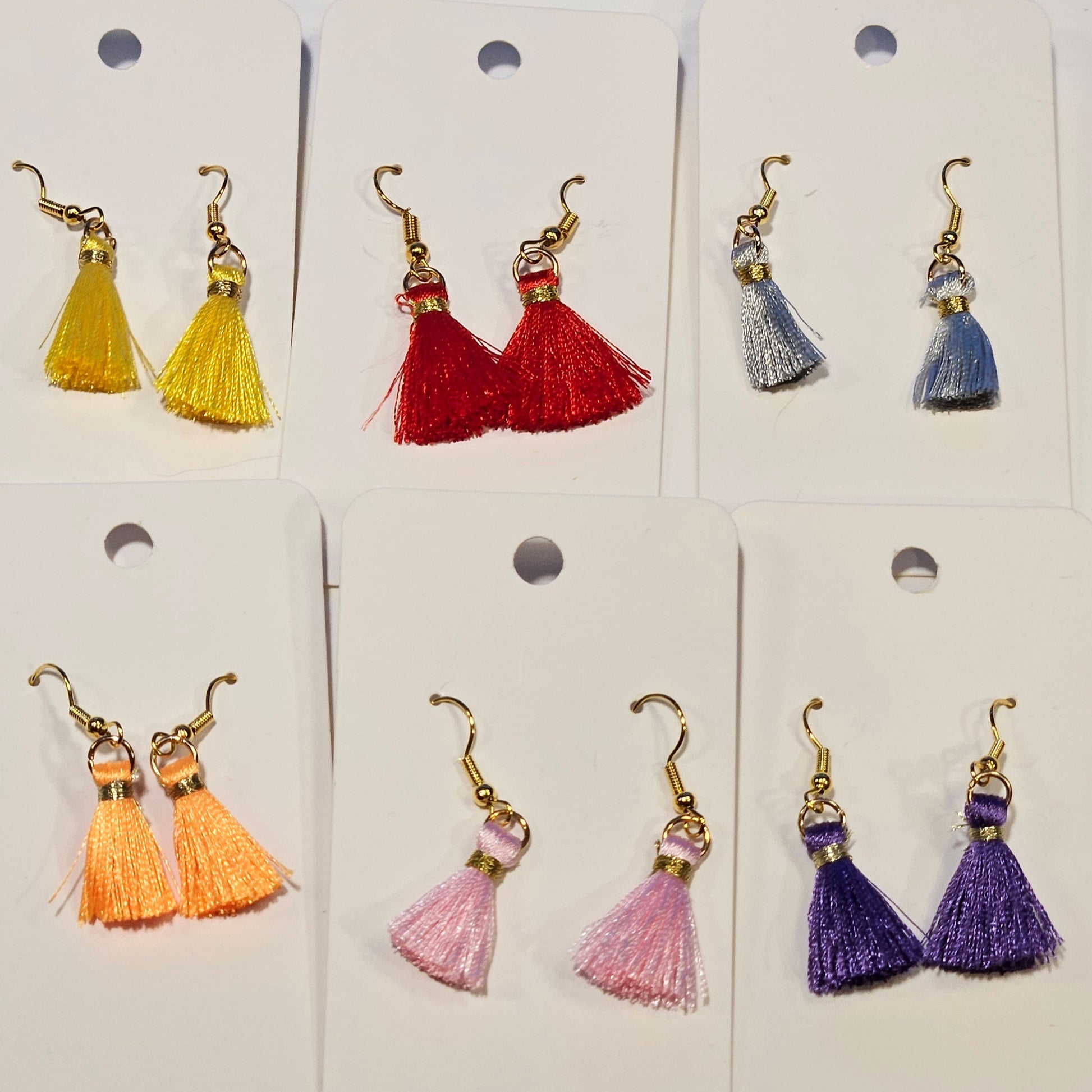 Set of colorful tassel earrings on display cards against a white background