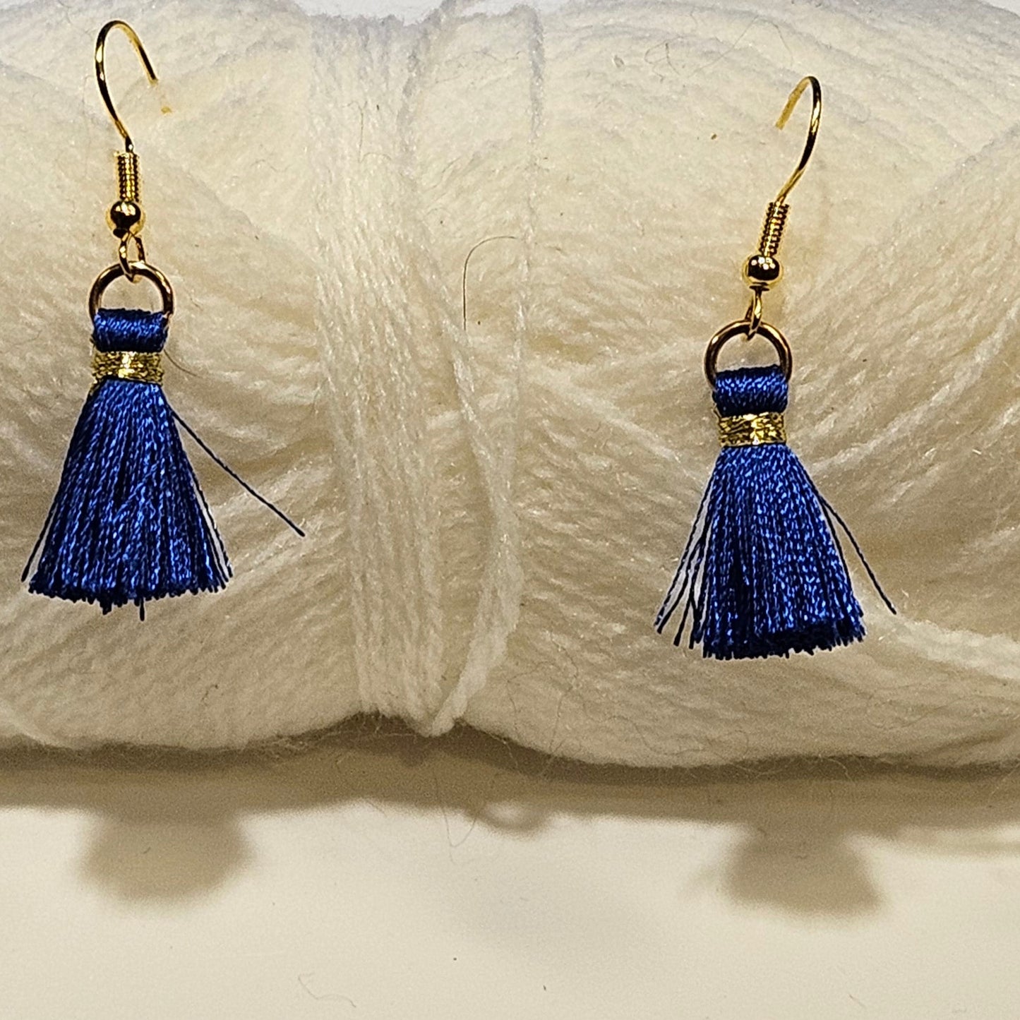 Blue tassel earrings displayed in front of a ball of white yarn.