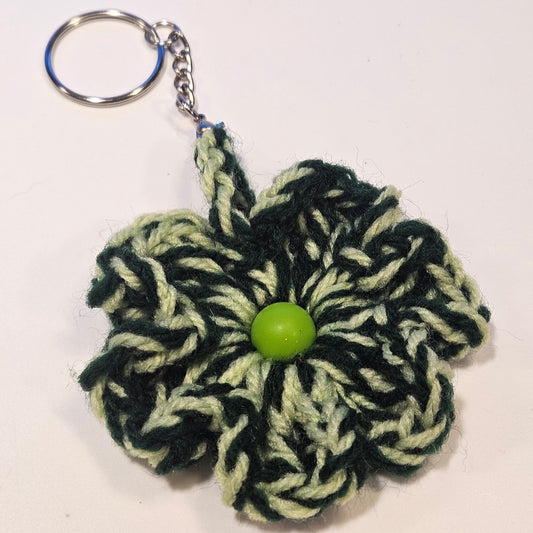 Crocheted flower keychain with a green button center on a white background