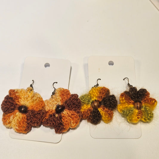 Pair of crocheted flower earrings on white cards against a white background