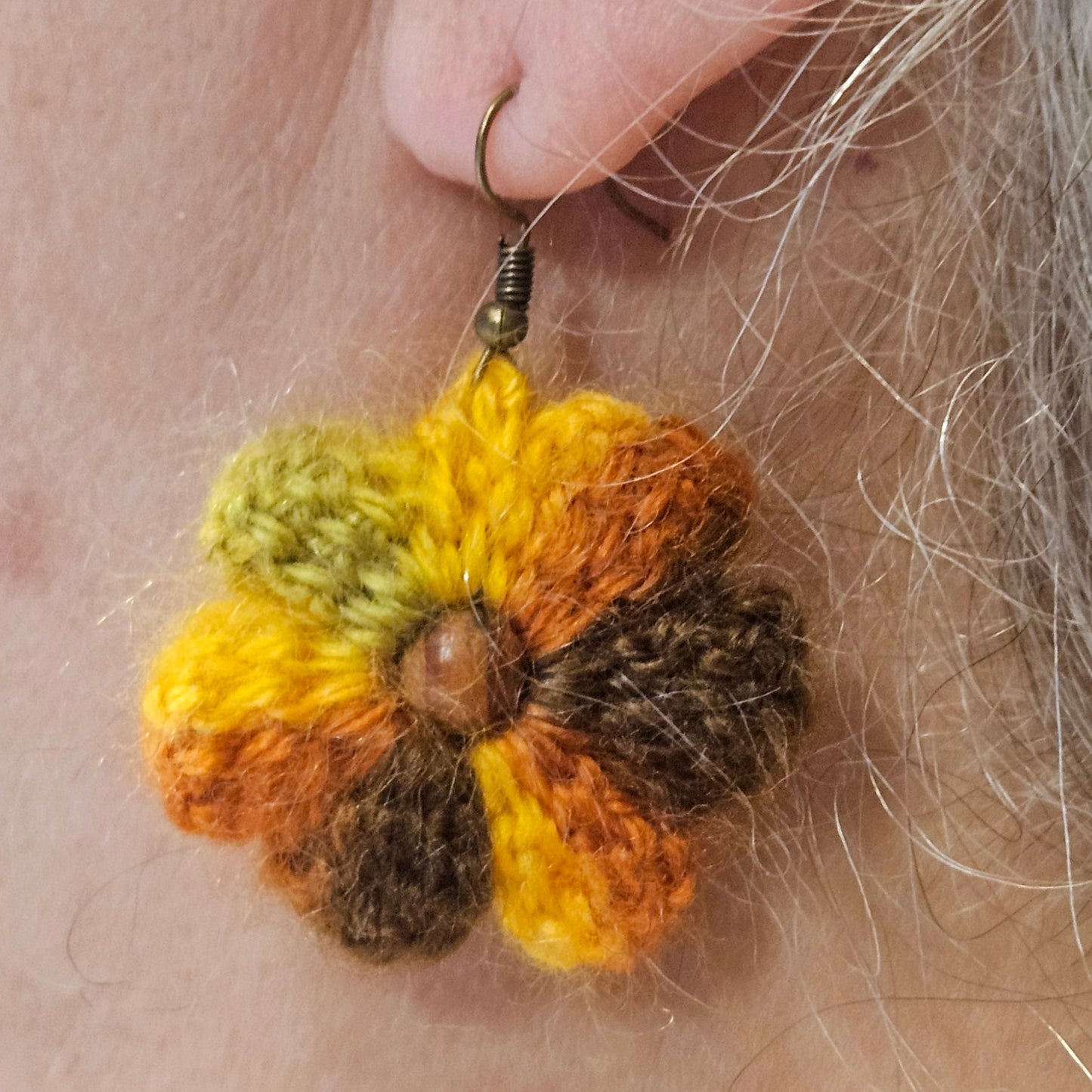 Close-up of a person wearing a colorful flower-shaped earring.