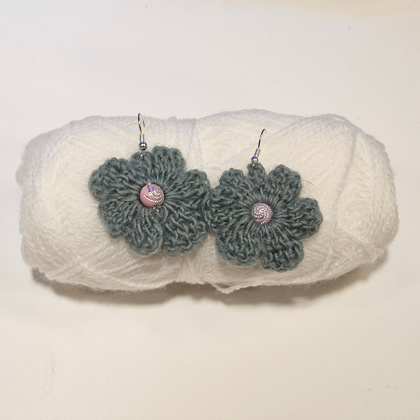 Pair of gray crochet flower earrings on a white textured surface