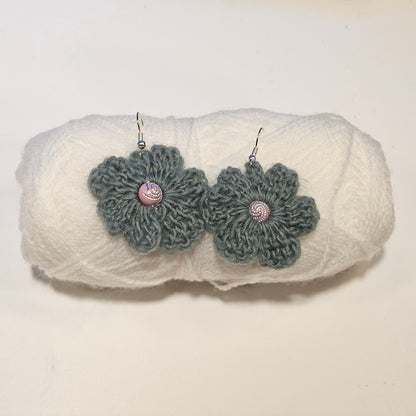 Pair of gray crochet flower earrings on a white textured surface