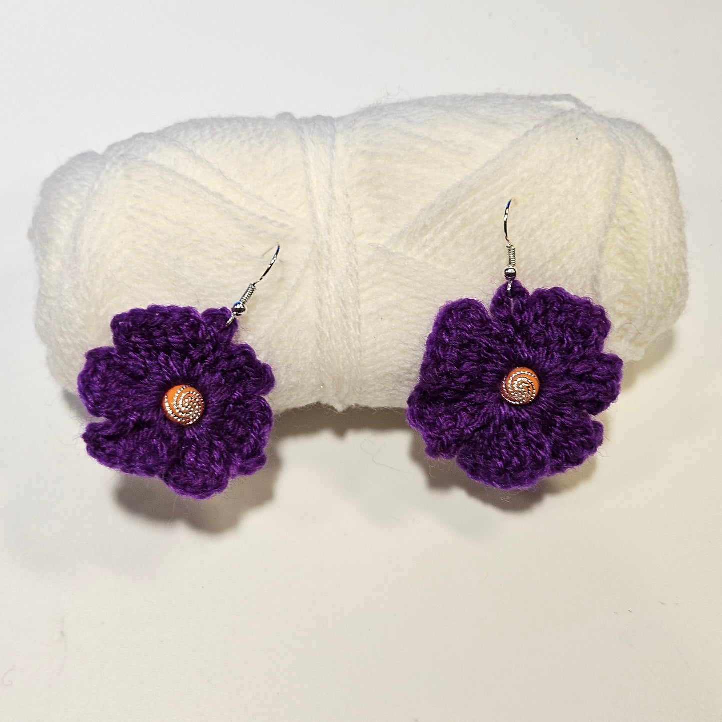 Purple crocheted flower earrings with gold centers on a white background