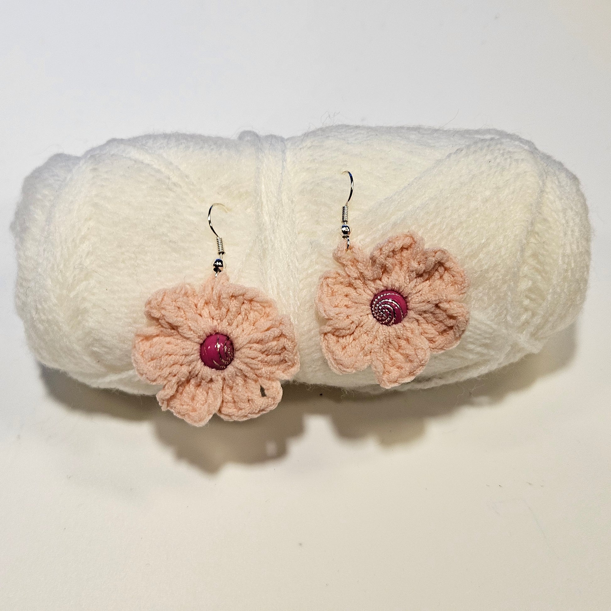 Crocheted flower earrings with pink centers on a white background