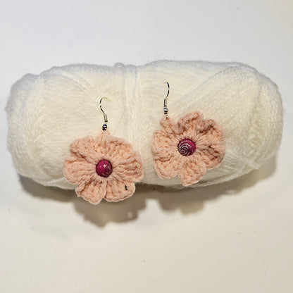 Crocheted flower earrings with pink centers on a white background