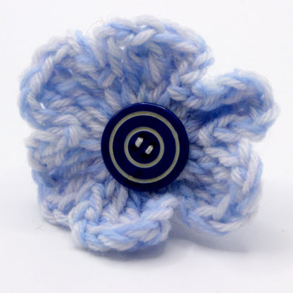 Blue knitted flower with a button center on a white background
