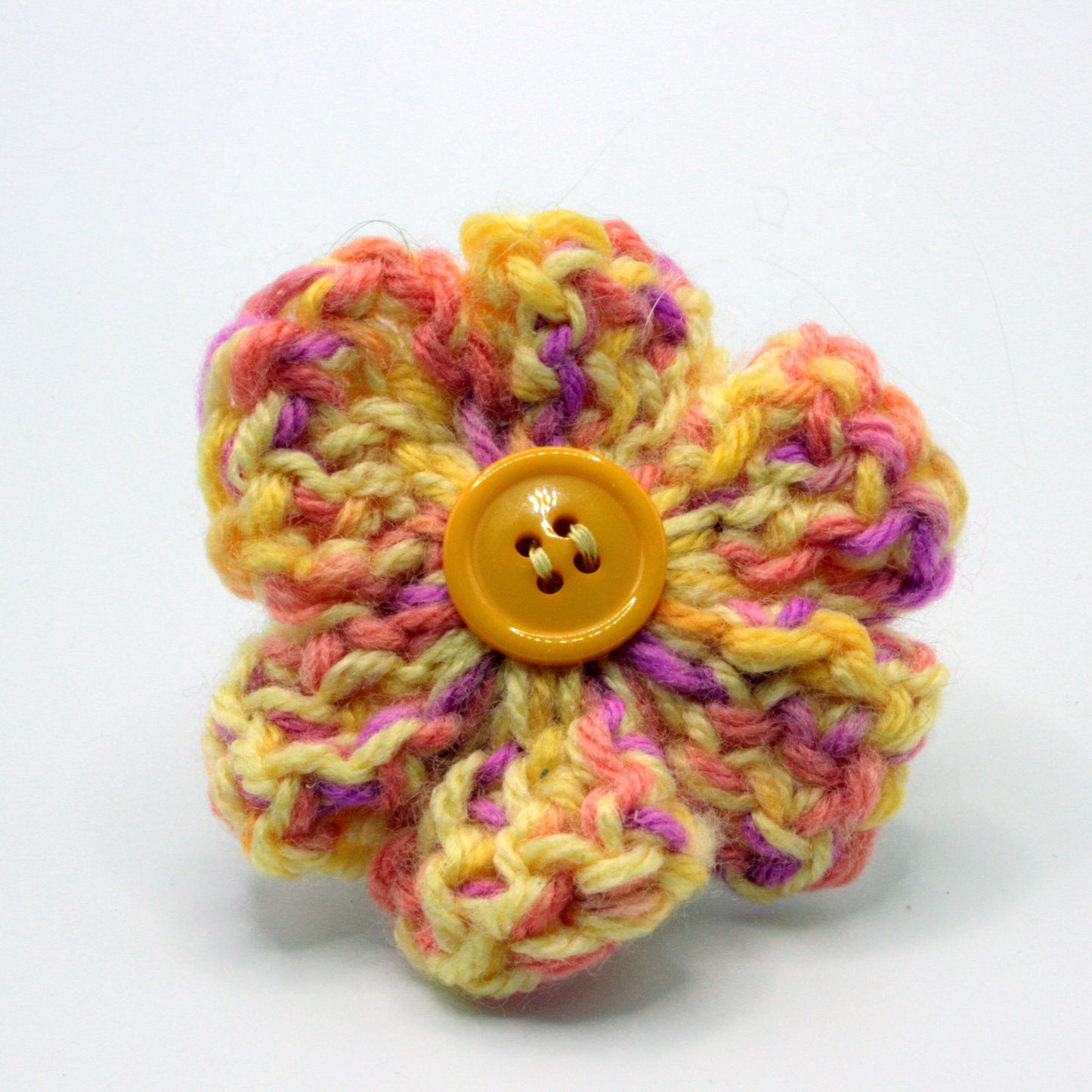 Colorful knitted flower with a button center on a white background