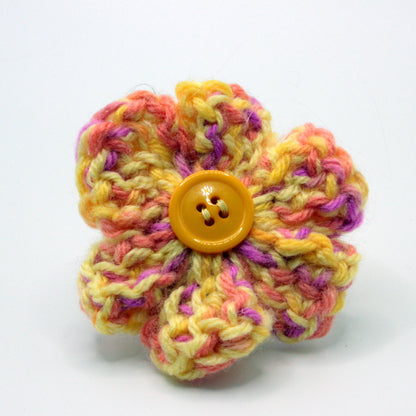 Colorful knitted flower with a button center on a white background