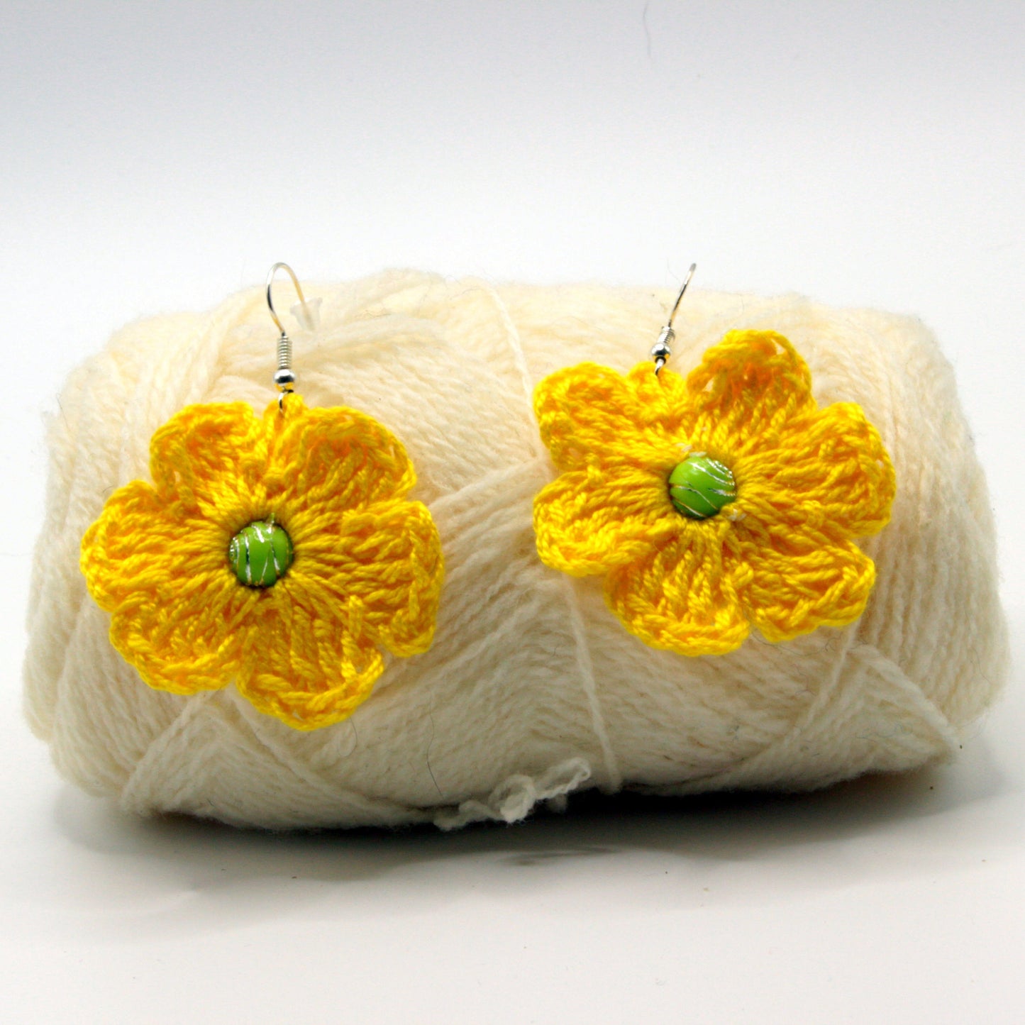 Yarn ball with yellow flower earrings on a white background