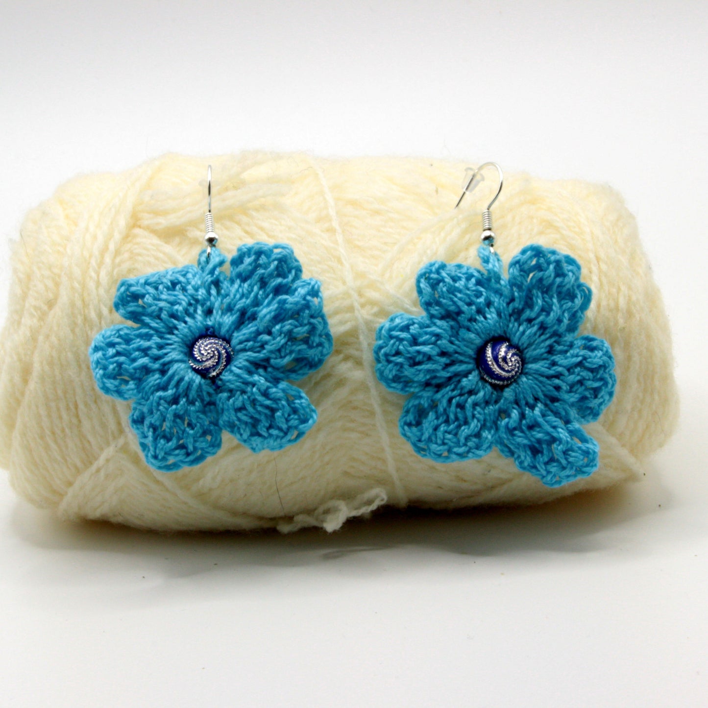 White yarn ball with blue flower-shaped ends on a white background